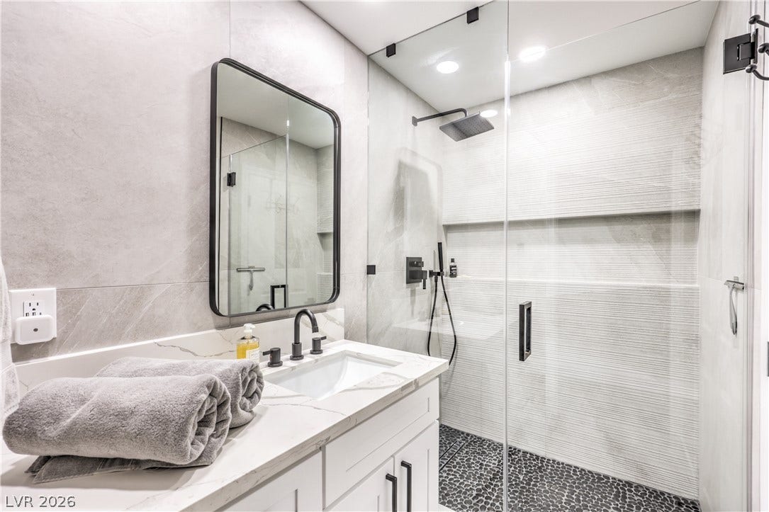 8211 Round Hills Circle, Las Vegas, NV 89113 This primary bathroom features a contemporary vanity with a sleek mirror and a spacious walk-in shower.