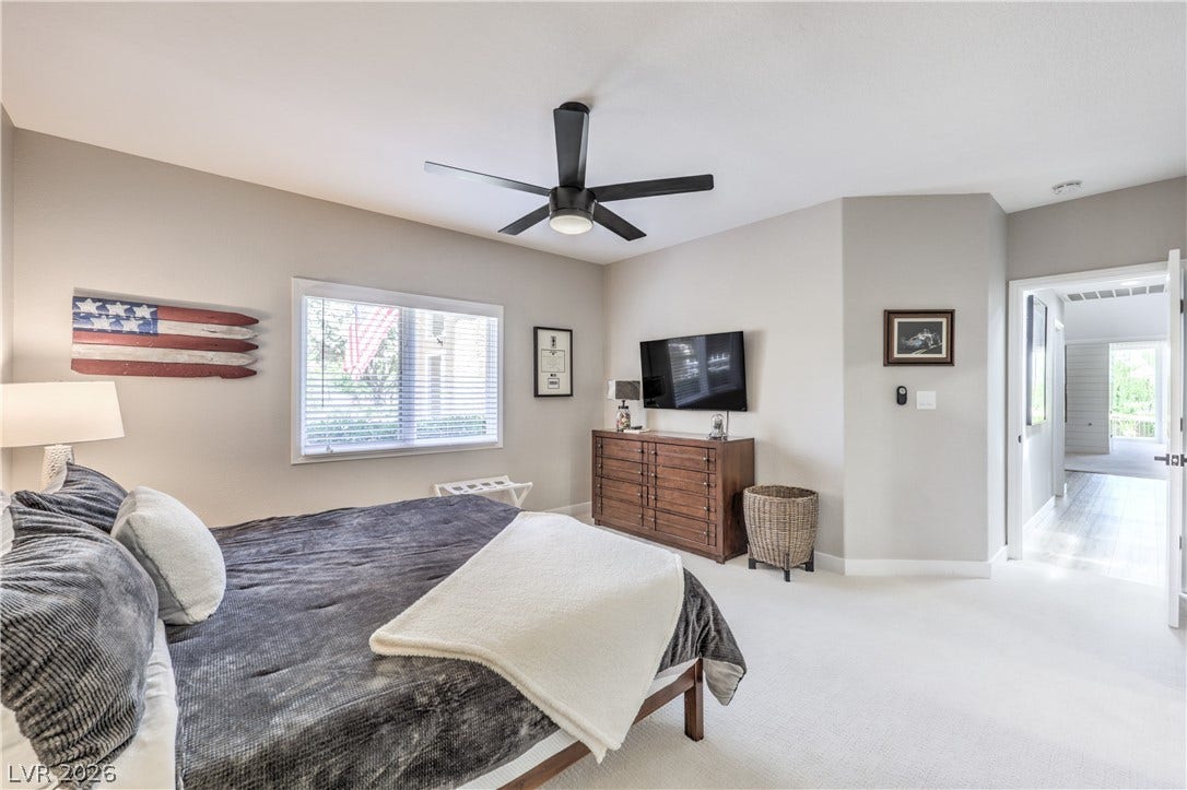 8211 Round Hills Circle, Las Vegas, NV 89113 Relax in this tranquil bedroom, featuring a large window with blinds and a sleek ceiling fan.