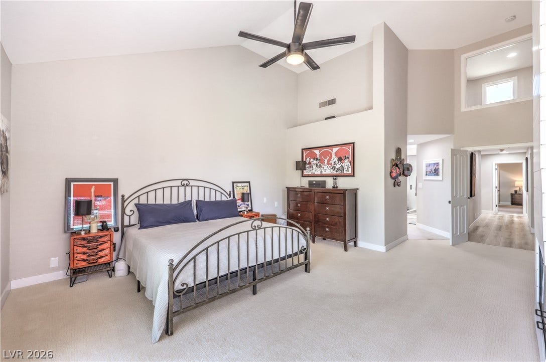 8211 Round Hills Circle, Las Vegas, NV 89113 This primary bedroom impresses with soaring vaulted ceilings and plush carpet, offering a serene and spacious retreat.