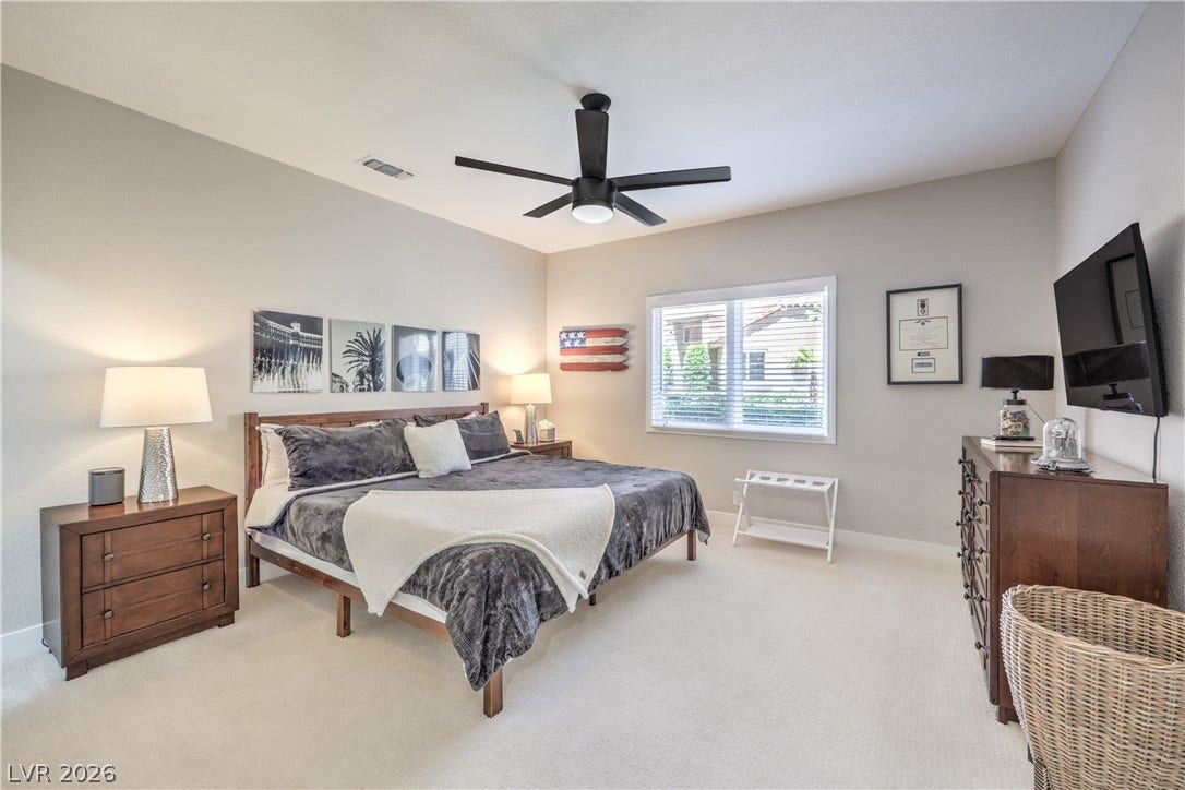 8211 Round Hills Circle, Las Vegas, NV 89113 This naturally illuminated bedroom offers carpeted flooring and a window with blinds, creating a serene and inviting personal retreat.