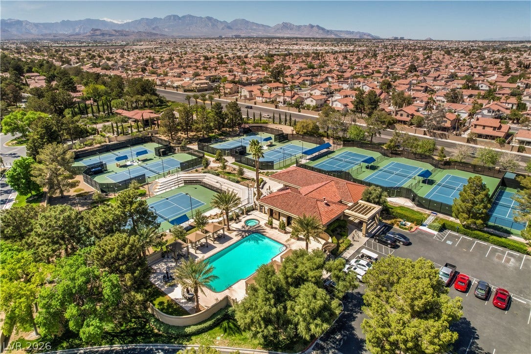 8211 Round Hills Circle, Las Vegas, NV 89113 An aerial perspective showcases a vibrant community with tennis courts, a resort-style pool, and ample parking surrounded by lush landscaping.