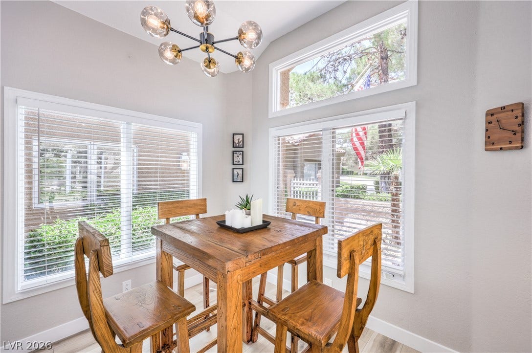 8211 Round Hills Circle, Las Vegas, NV 89113 This naturally illuminated dining area features a warm wooden table and chairs, set against a backdrop of ample windows.