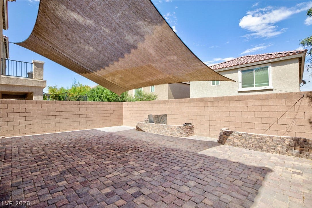 9804 Kodiak Island Court, Las Vegas, NV 89141 An expansive paver patio sits under a large shade sail within a private block-walled yard.