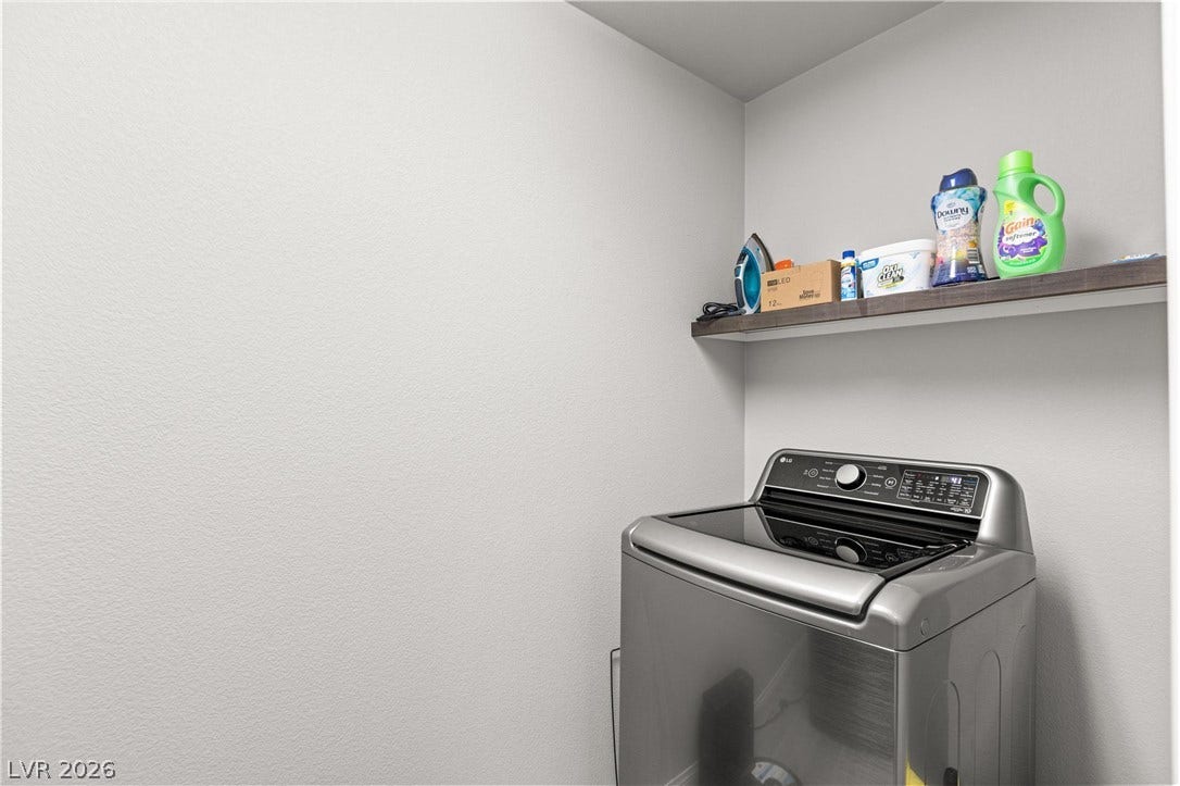 9804 Kodiak Island Court, Las Vegas, NV 89141 A functional laundry area includes a floating wooden shelf mounted on smooth walls.