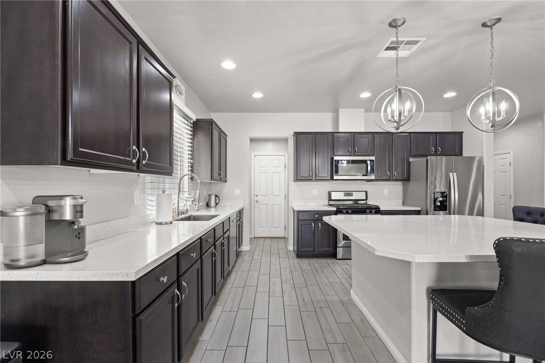 9804 Kodiak Island Court, Las Vegas, NV 89141 Rich dark cabinetry contrasts beautifully with gleaming stone countertops in this modern kitchen design.