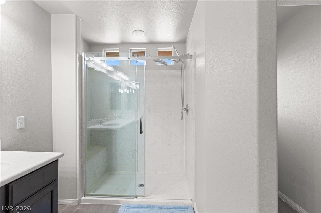 9804 Kodiak Island Court, Las Vegas, NV 89141 High ceilings and a glass-enclosed shower elevate this modern bathroom design.
