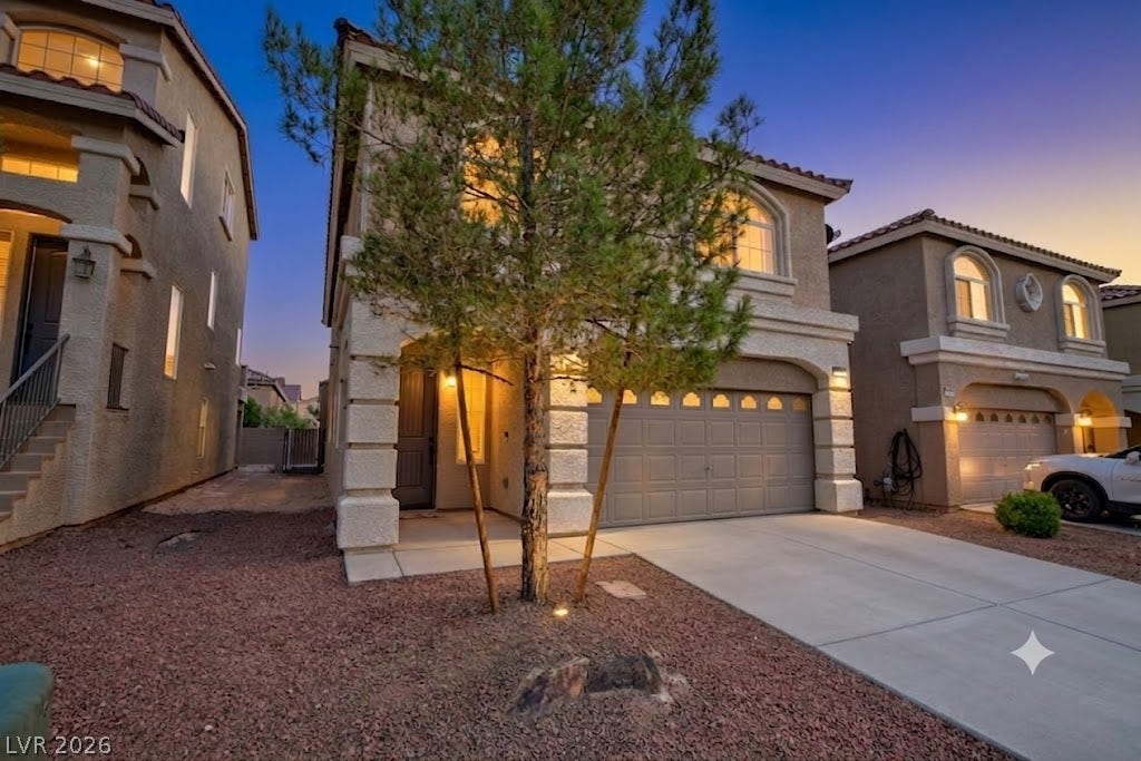 9804 Kodiak Island Court, Las Vegas, NV 89141 Stucco exterior elements and a paved concrete driveway define this multi-level home under twilight skies.