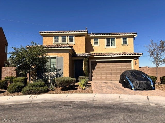 2449 Range Creek, Henderson, NV 89044 Mediterranean-inspired facade highlights a stucco exterior alongside a paved driveway and two-car garage.