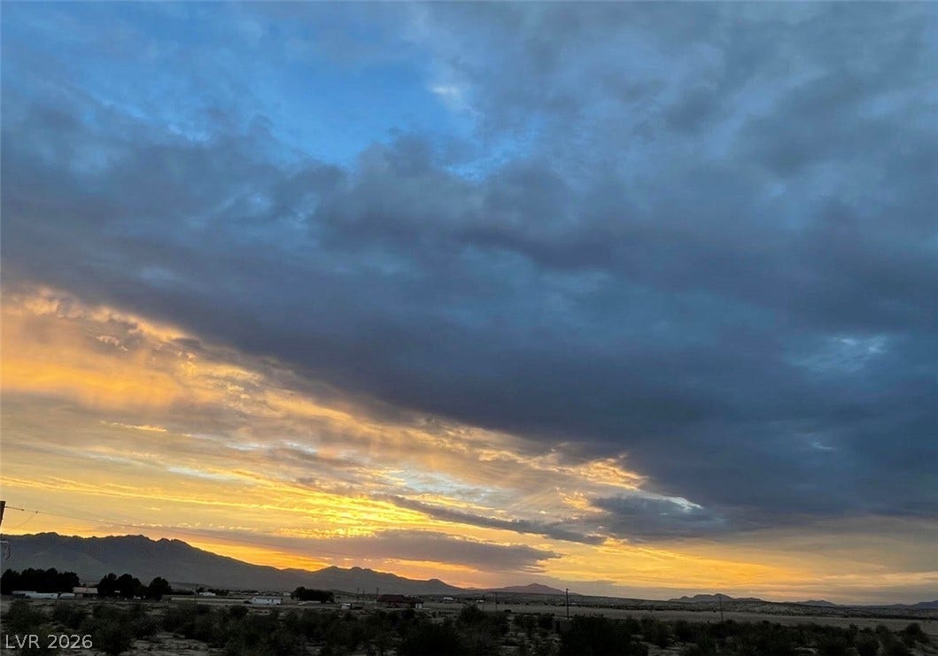 Vibrant sunset colors illuminate the sky above distant mountain ranges and desert terrain.