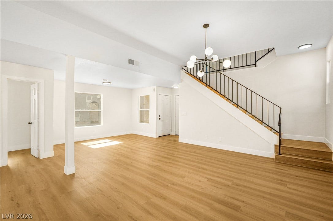 Gleaming wood floors anchor a wide-open living area below a prominent modern staircase.