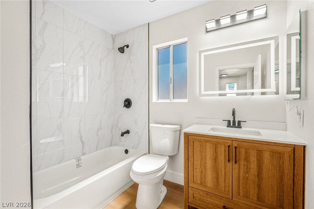 Marble-patterned tile shower walls and a warm wood vanity create a modern aesthetic.