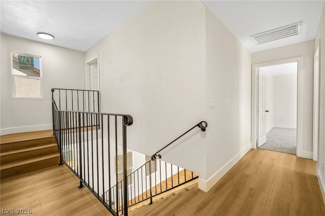 Gleaming wood floors and a custom iron railing define this airy upper level landing.