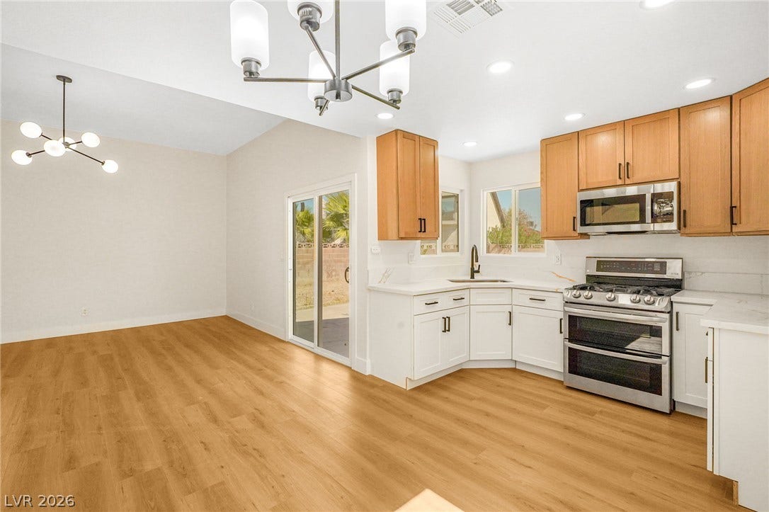 An open dining and kitchen area showcases warm wood flooring and sliding glass patio doors.