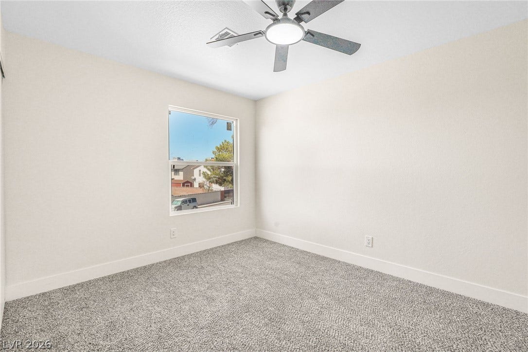 Plush carpeting and a picture window define this comfortable bedroom space.