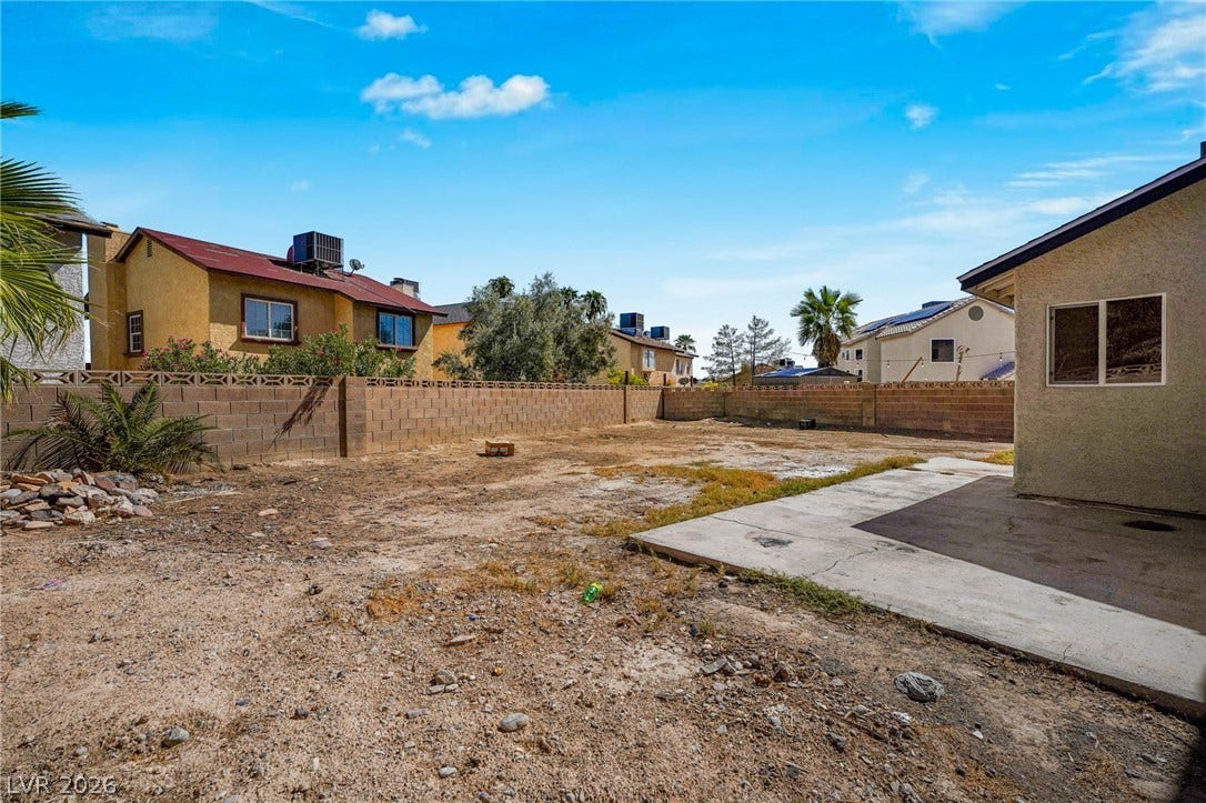 A spacious backyard awaits customization alongside a concrete patio slab and enclosing block walls.