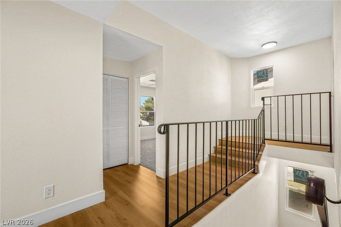 Warm wood flooring and clean lines define this multi-level landing space with metal railings.