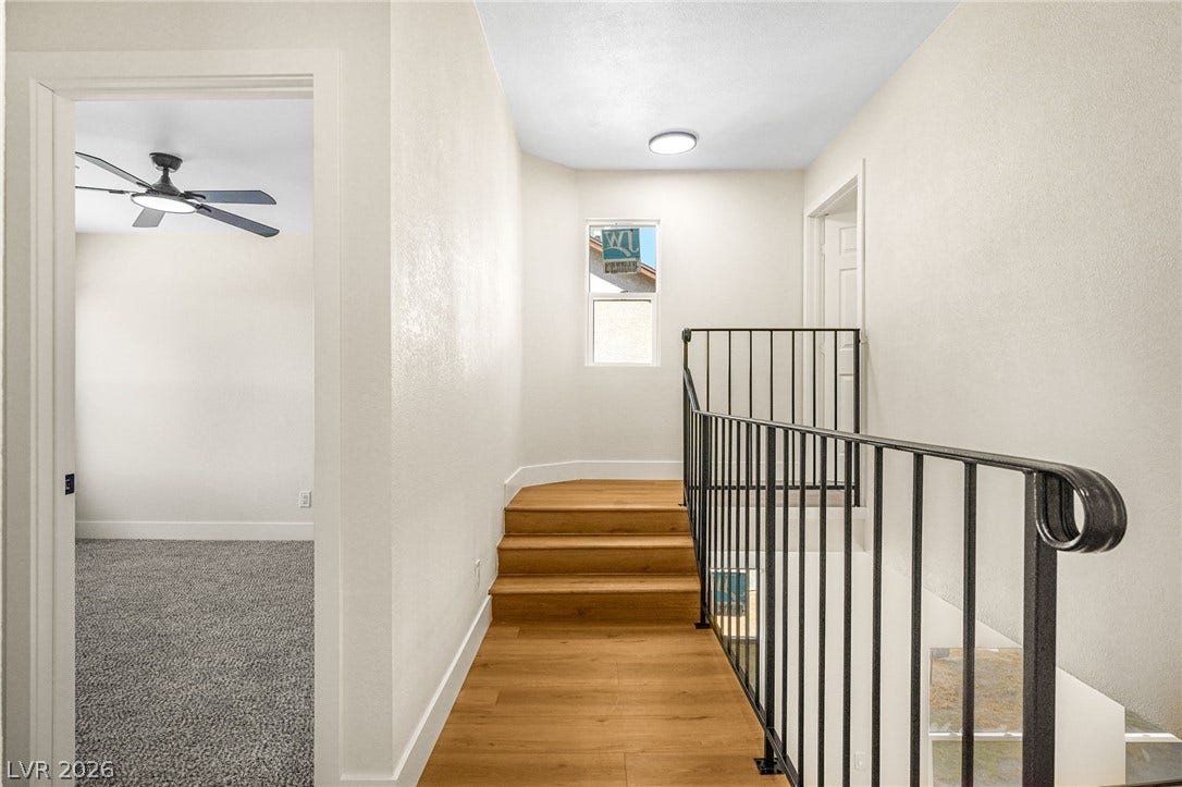 Gleaming hardwood floors and a modern metal railing define this bright upstairs landing.