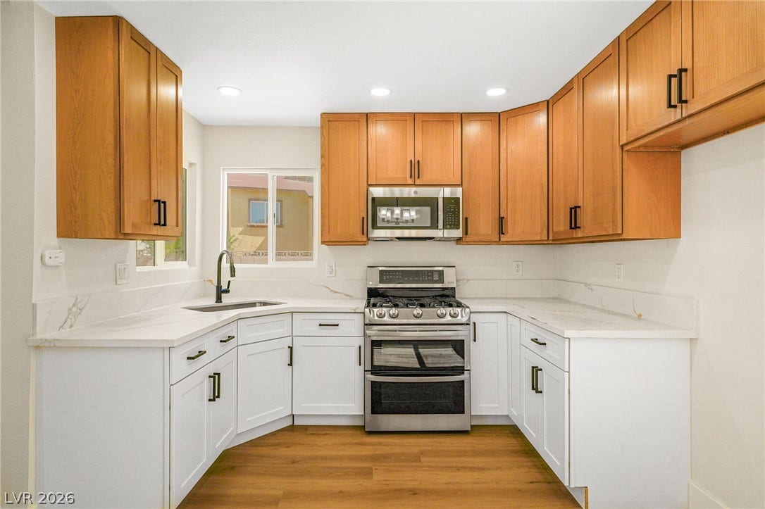 Warm wood cabinetry pairs with crisp white lower cabinets and stone counters in this updated kitchen.