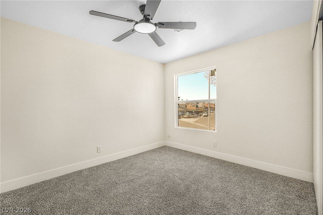 Soft carpeting pairs with neutral walls and a single window in this quiet space.