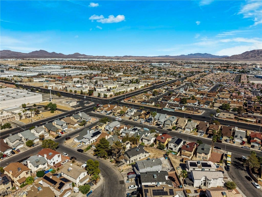 An expansive neighborhood vista unfolds beneath clear blue skies, framed by distant mountain ranges.