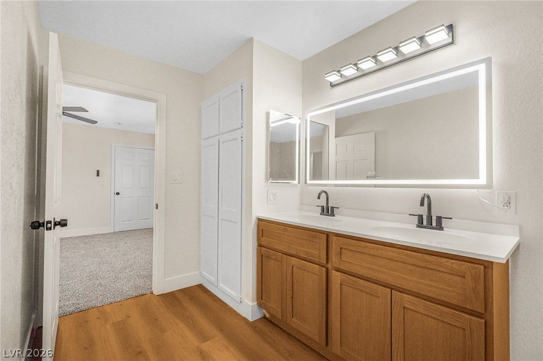 A modern double vanity anchors this bright bathroom featuring warm wood-look floors.