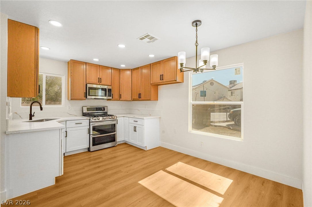 Warm wood floors and dual-toned cabinetry anchor this inviting kitchen and adjacent dining space.