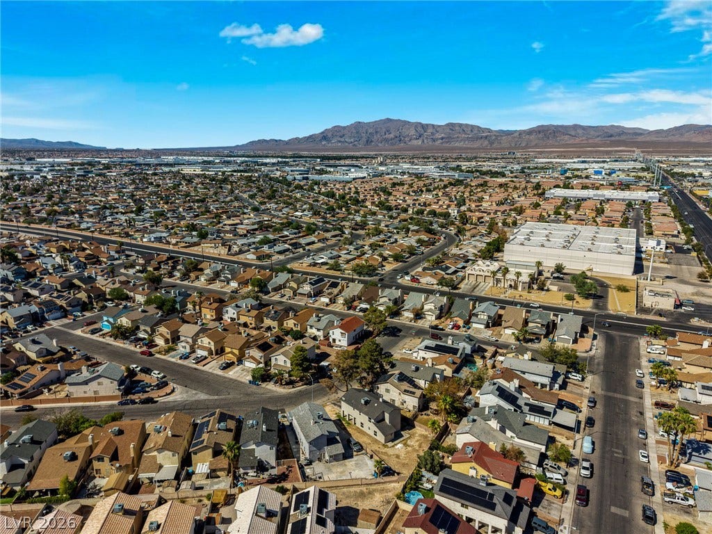 Distant mountain ranges border this expansive suburban community under clear blue skies.