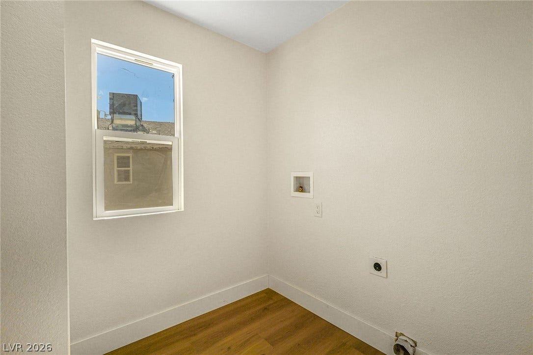 Natural light pours through a single window onto wood flooring in this designated utility space.
