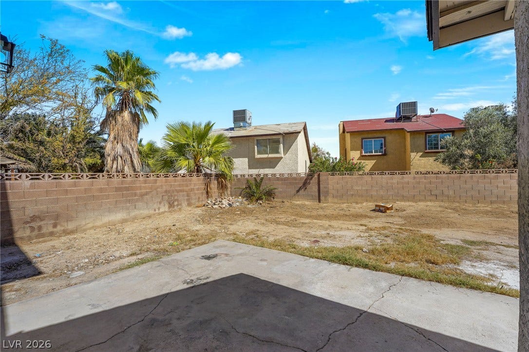 A spacious backyard awaits customization with its concrete patio and sturdy block wall fencing.
