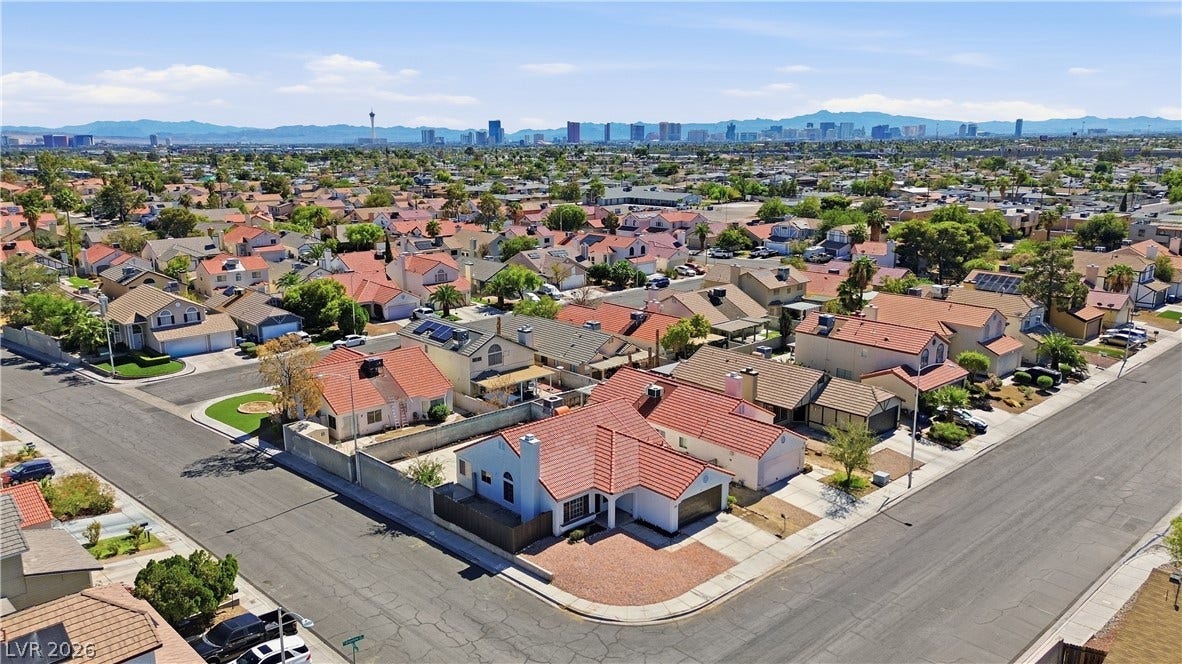 1013 Greystone Drive, Las Vegas, NV 89108 An aerial perspective showcases a quiet residential neighborhood set against a distant city skyline.