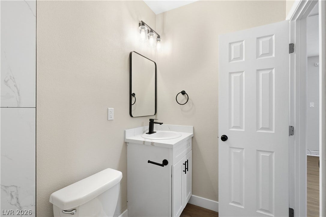1013 Greystone Drive, Las Vegas, NV 89108 A classic six-panel door opens into a neutral-toned powder room with a white vanity.