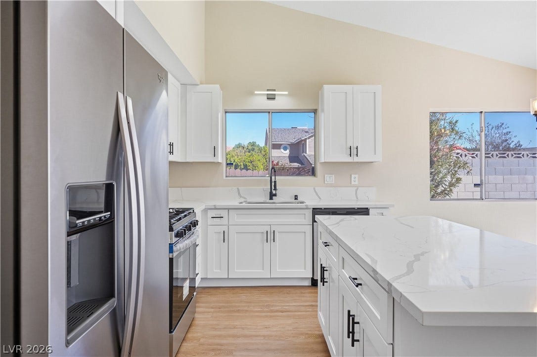 1013 Greystone Drive, Las Vegas, NV 89108 Vaulted ceilings soar over a modern kitchen complete with stone countertops and a spacious island.