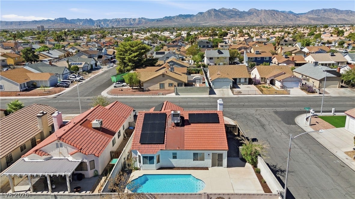 1013 Greystone Drive, Las Vegas, NV 89108 An aerial perspective showcases a backyard pool and rooftop solar panels set against majestic mountain views.