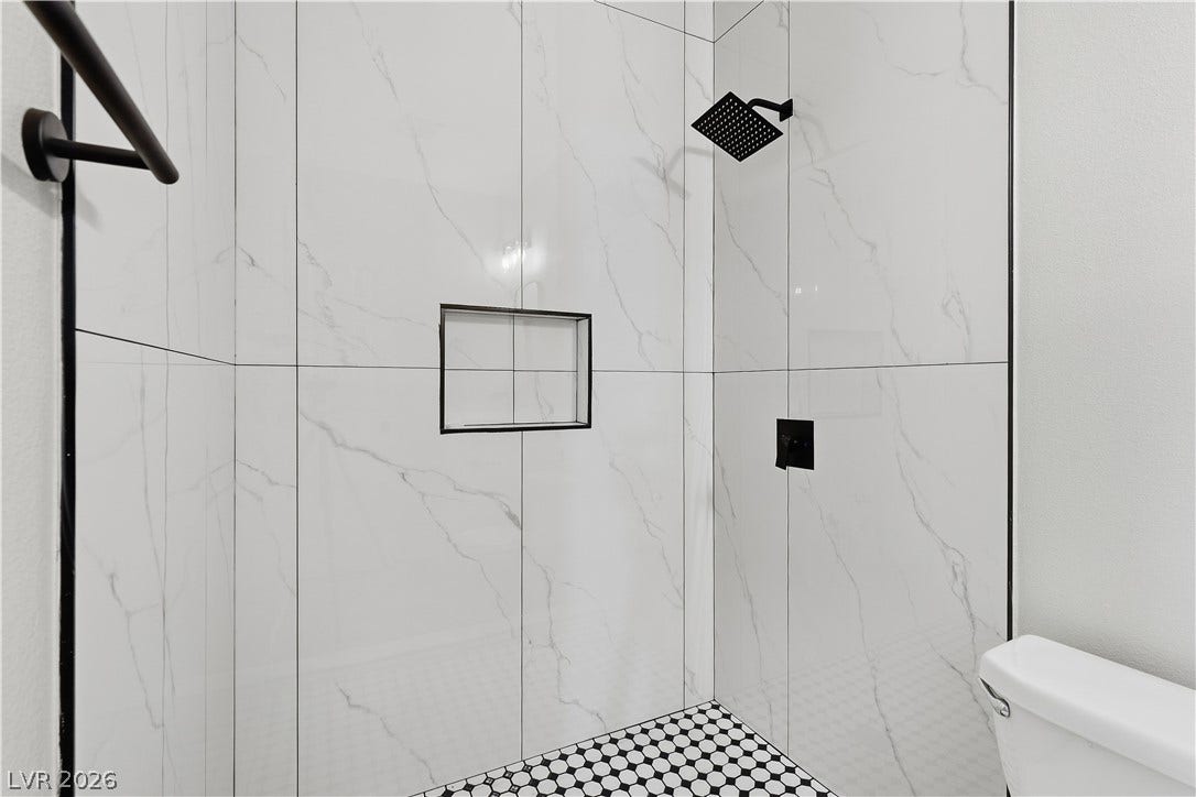 1013 Greystone Drive, Las Vegas, NV 89108 Elegantly tiled walk-in shower features modern matte black fixtures and a built-in recessed niche.
