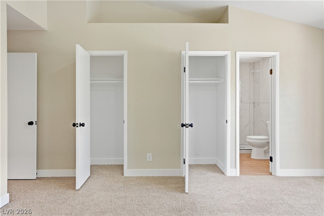 1013 Greystone Drive, Las Vegas, NV 89108 A spacious bedroom features neutral carpeting, soaring vaulted ceilings, and dual closets alongside an attached bath.