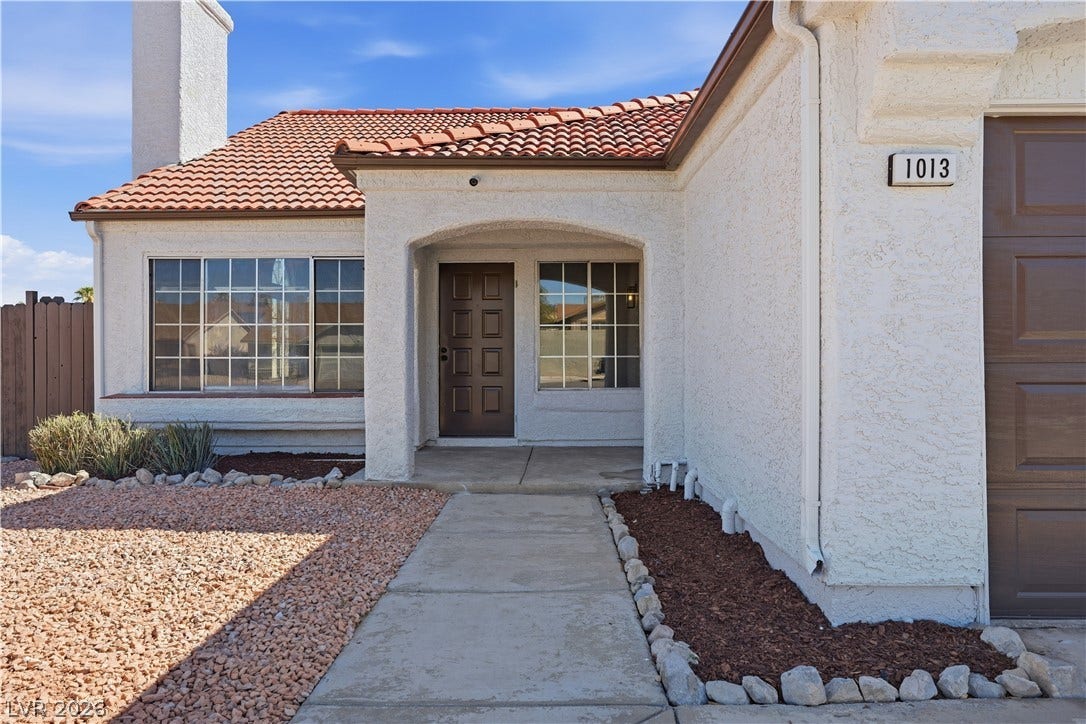 1013 Greystone Drive, Las Vegas, NV 89108 A concrete walkway leads under an arched entryway to the front door of this home.