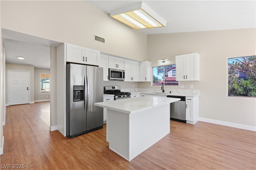 1013 Greystone Drive, Las Vegas, NV 89108 High ceilings and a central island define this modern kitchen with warm wood flooring.