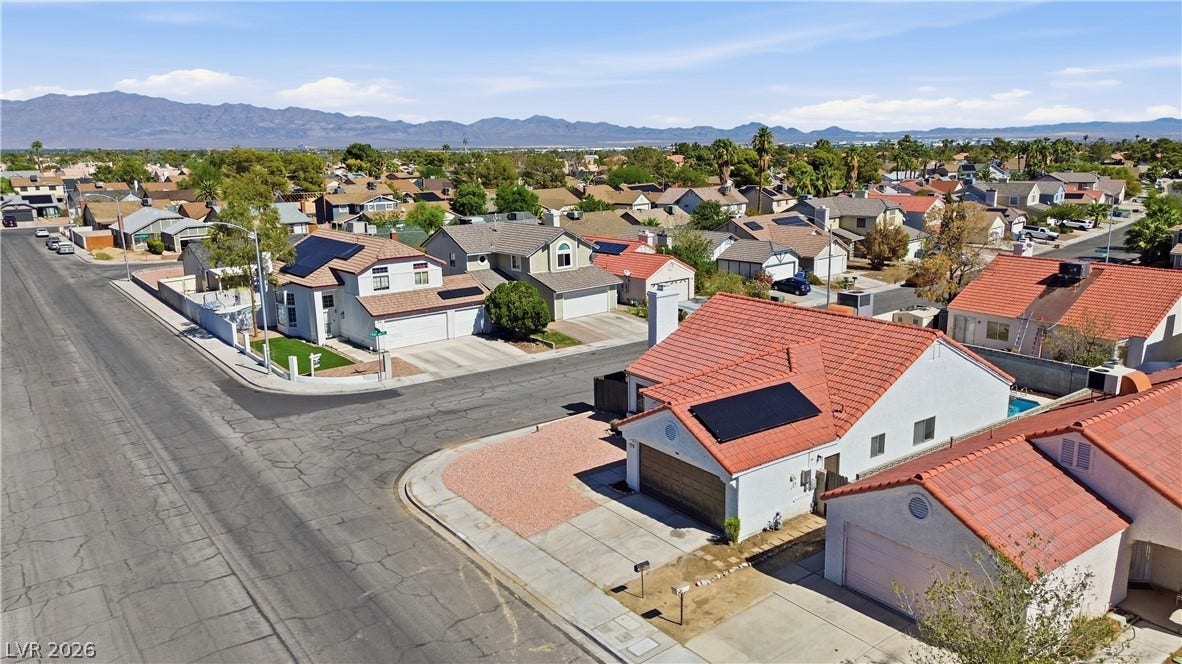 1013 Greystone Drive, Las Vegas, NV 89108 Distant mountains frame a quiet suburban neighborhood featuring homes with tile roofing and solar panels.