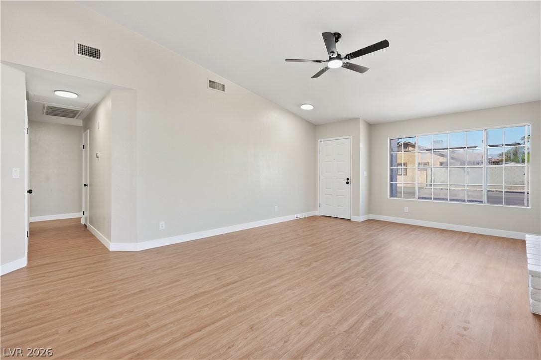 1013 Greystone Drive, Las Vegas, NV 89108 Warm wood-style flooring and vaulted ceilings create an open, airy atmosphere in this main living space.
