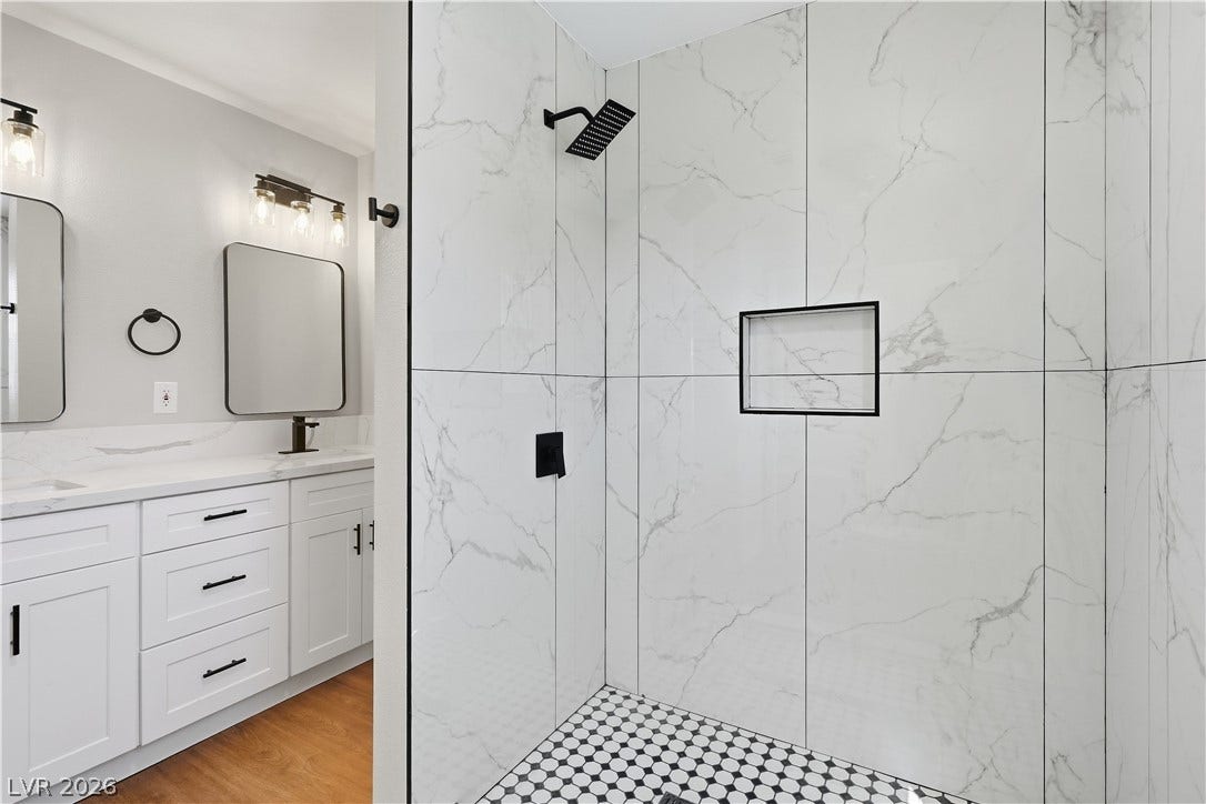 1013 Greystone Drive, Las Vegas, NV 89108 A modern walk-in shower features marble-look tiling and contrasting black fixtures.