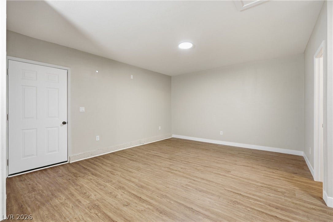1013 Greystone Drive, Las Vegas, NV 89108 A spacious room features durable wood-look flooring and clean neutral walls.