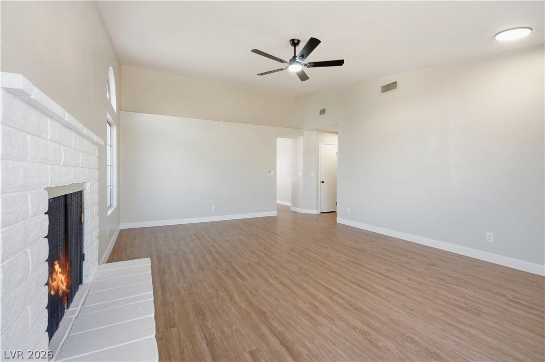 1013 Greystone Drive, Las Vegas, NV 89108 Warm wood flooring and a classic brick fireplace anchor this airy living space.