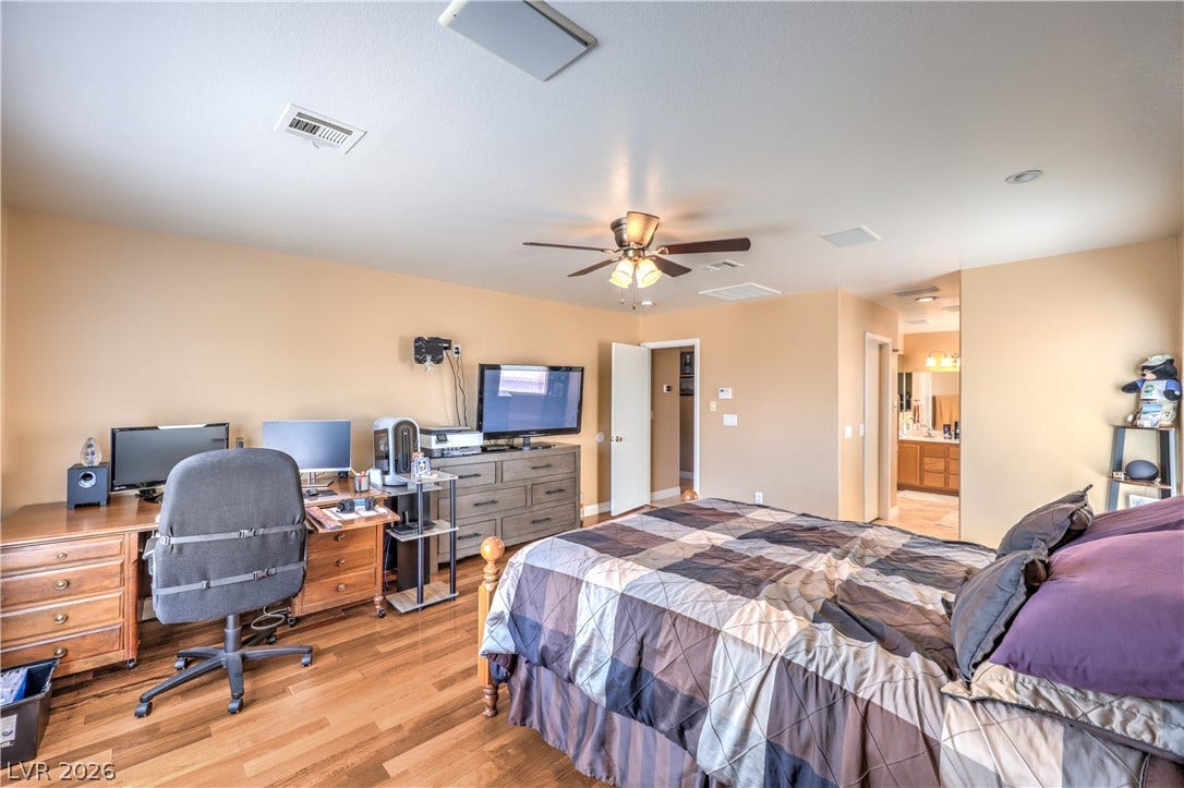 Gleaming wood-laminate floors and recessed lighting anchor this functional primary bedroom suite.