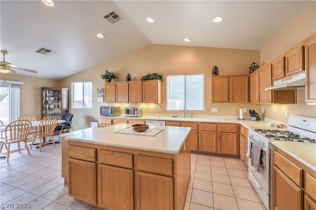 Vaulted ceilings and tile flooring enhance this open kitchen equipped with a central island.