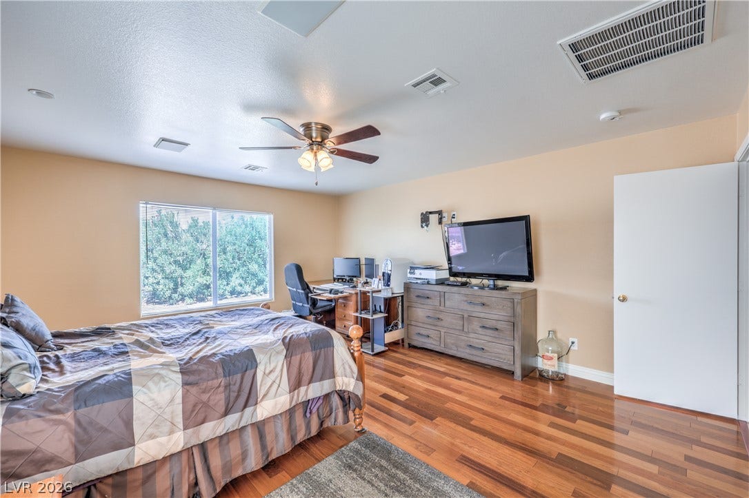 Rich wood-laminate flooring complements the spacious layout, illuminated by abundant natural light.