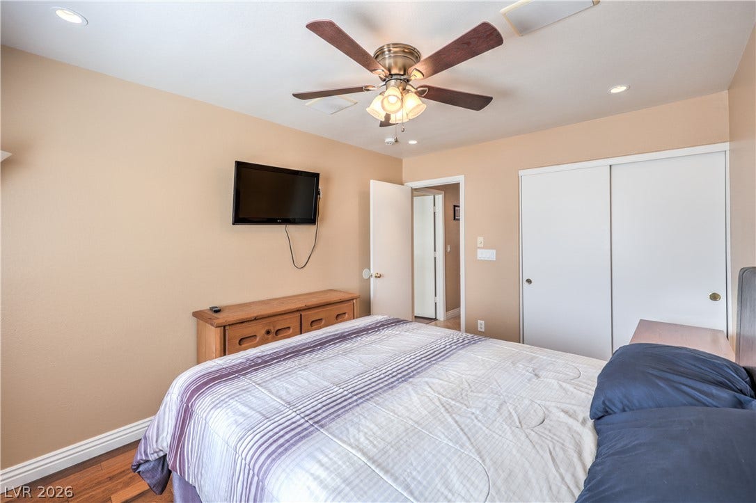Rich wood-laminate flooring complements the smooth walls and classic trim molding of this inviting bedroom space.