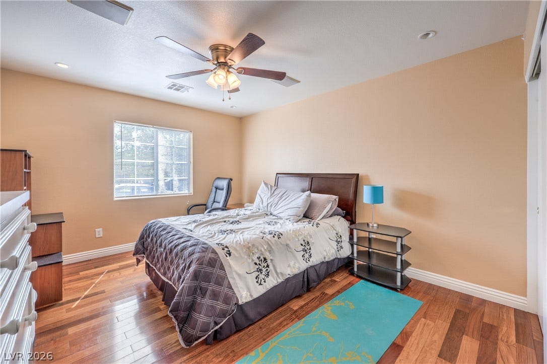 Gleaming wood-laminate floors and a wide window define this comfortable bedroom space.
