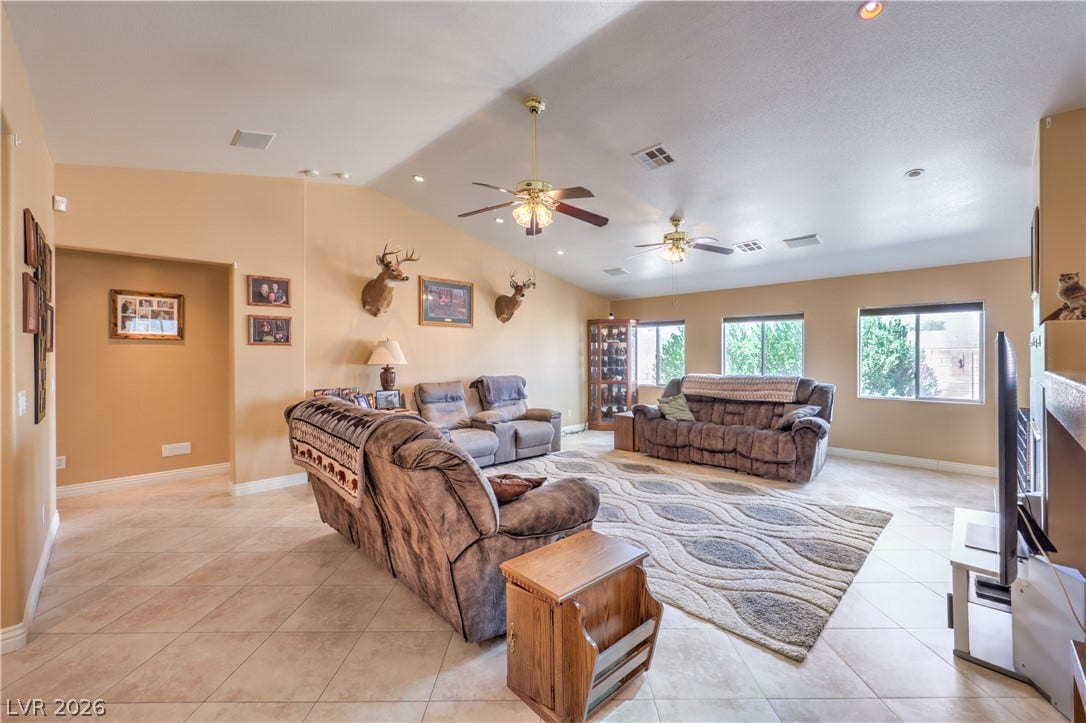An open floorplan living area showcases  tile flooring and vaulted ceilings.