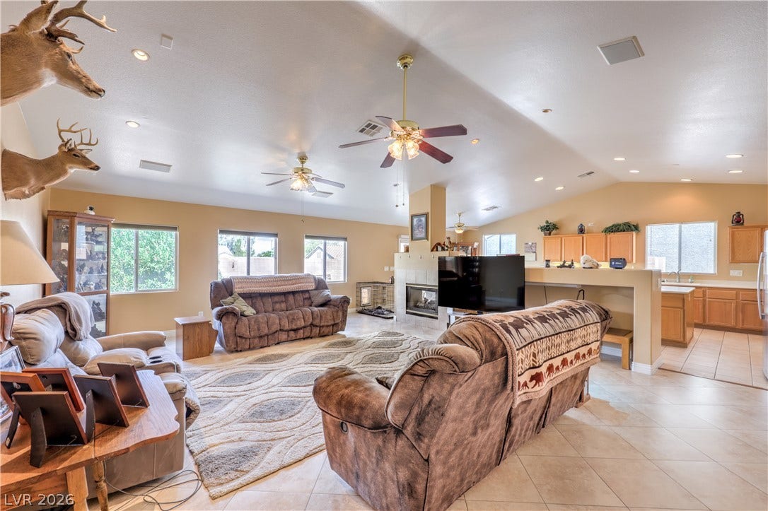 A spacious living room features tile flooring and vauted ceilings.