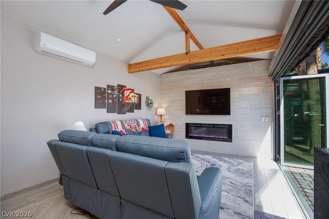 8175 Arville Street, #142, Las Vegas, NV 89139 Exposed wood trusses and a sleek fireplace wall elevate this bright living area.